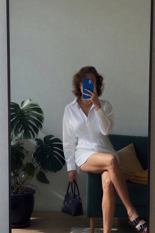 brunette,white skin,slim body,medium breasts,cleavage,shirt dress,white shirt,long hair,sitting on couch,mirror selfie,teaser,legs crossed,handbag