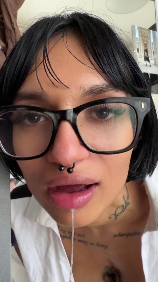 black hair,brunette,white skin,slim body,glasses,septum piercing,nose ring,white shirt,open shirt,spit drip,tongue out,close up face,selfie,green eyeliner